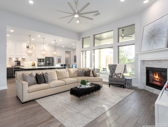 living room featuring a fireplace, ceiling fan with notable chandelier, and light hardwood / wood-style floors