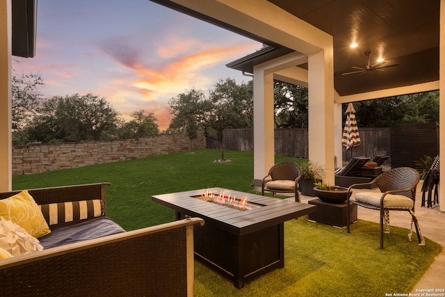 patio terrace at dusk featuring a yard and a fire pit