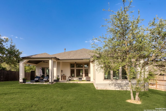 rear view of property featuring a lawn, ceiling fan, a patio area, and an outdoor hangout area