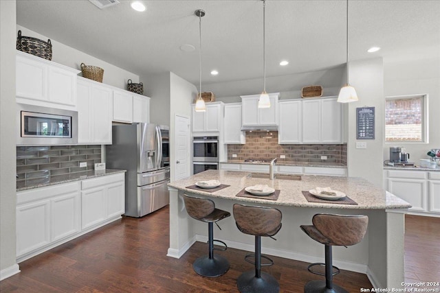 kitchen featuring tasteful backsplash, decorative light fixtures, white cabinetry, and appliances with stainless steel finishes