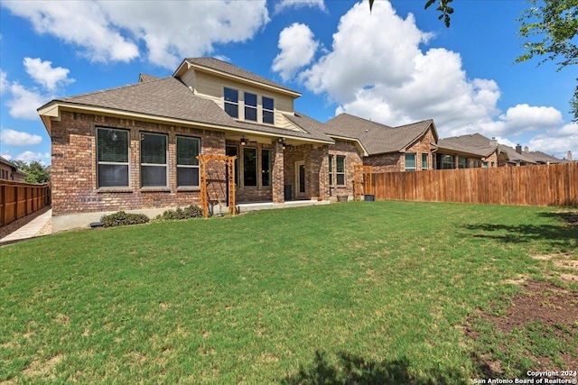 rear view of property with a yard and a patio