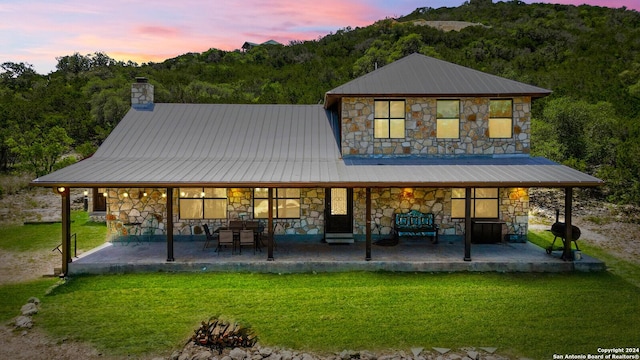 back house at dusk featuring a lawn