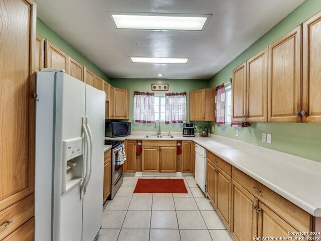 kitchen with sink, light tile patterned floors, and white appliances