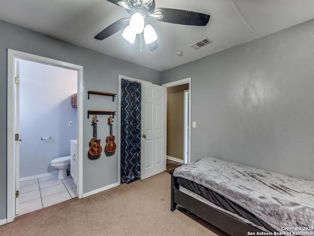 bedroom featuring baseboards, ensuite bathroom, visible vents, and light colored carpet