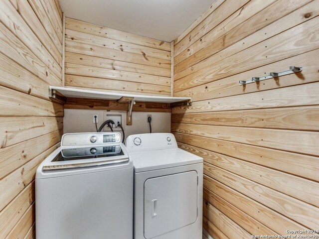 laundry room featuring wood walls and washer and dryer