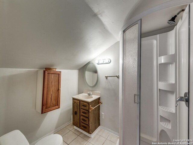 bathroom with tile patterned floors, vaulted ceiling, toilet, and vanity