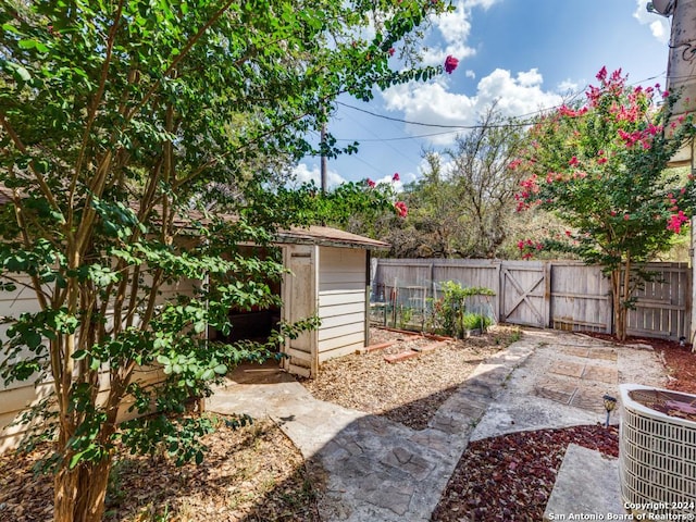 view of yard featuring cooling unit, a storage shed, an outdoor structure, fence, and a gate