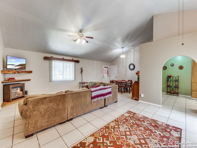 living room featuring light tile patterned floors, arched walkways, a glass covered fireplace, ceiling fan, and vaulted ceiling