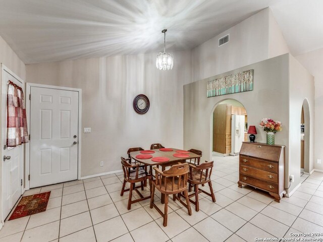 dining space featuring an inviting chandelier, high vaulted ceiling, and tile patterned floors