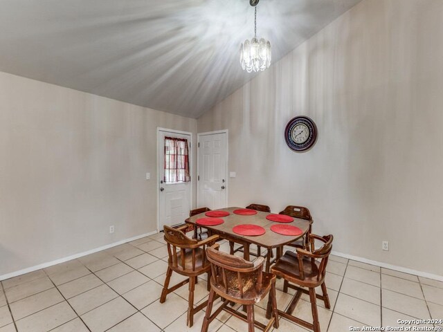 dining area with a notable chandelier, lofted ceiling, and light tile patterned floors