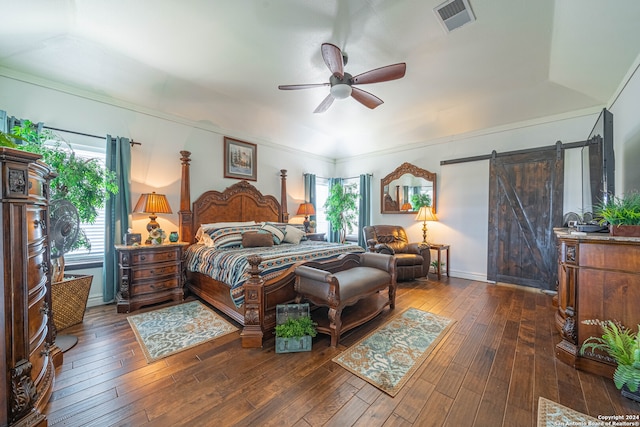 bedroom with ceiling fan, dark hardwood / wood-style flooring, and a barn door