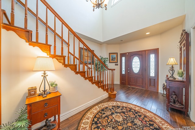 entryway with an inviting chandelier, a towering ceiling, and dark wood-type flooring