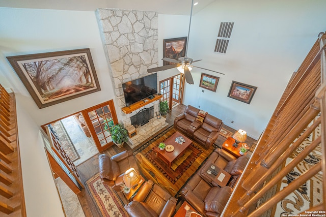 living room featuring hardwood / wood-style flooring, a fireplace, ceiling fan, and high vaulted ceiling