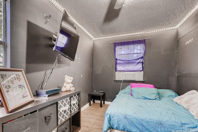 bedroom featuring cooling unit, crown molding, ceiling fan, a textured ceiling, and light hardwood / wood-style floors