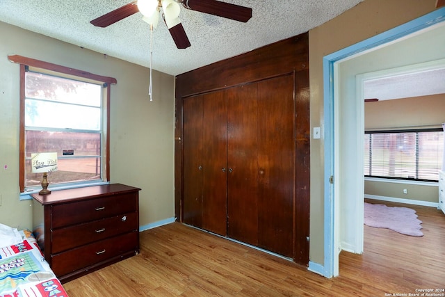 bedroom featuring ceiling fan, a closet, a textured ceiling, and light hardwood / wood-style flooring