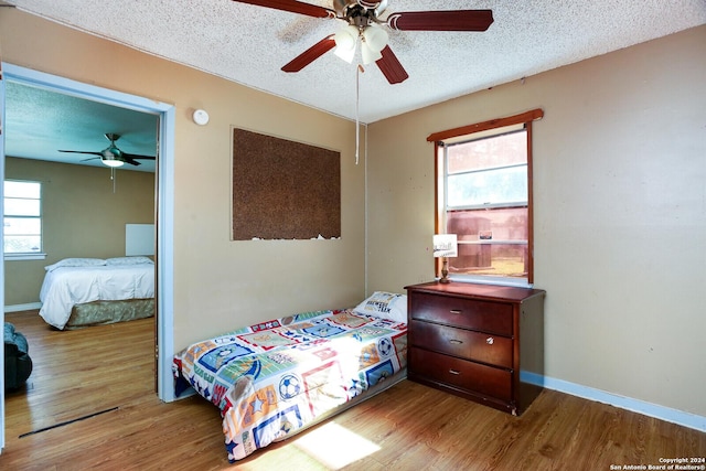 bedroom with ceiling fan, light wood-type flooring, and a textured ceiling