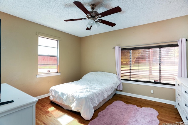 bedroom with multiple windows, ceiling fan, and hardwood / wood-style flooring