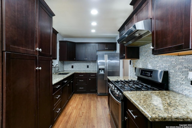 kitchen featuring backsplash, sink, exhaust hood, and appliances with stainless steel finishes