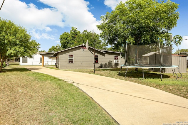 ranch-style house featuring a carport, a front yard, and a trampoline