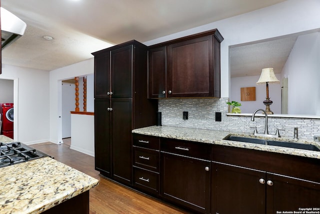 kitchen with decorative backsplash, light stone countertops, dark brown cabinetry, sink, and light hardwood / wood-style flooring