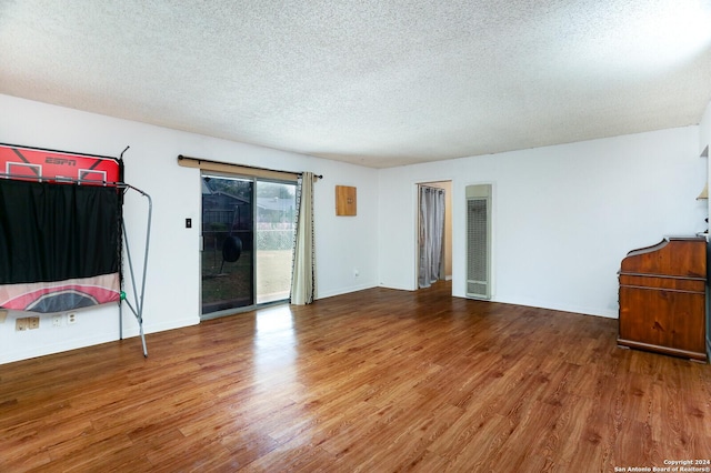 empty room with wood-type flooring and a textured ceiling