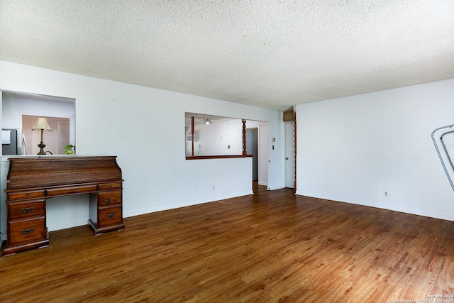 unfurnished living room with dark hardwood / wood-style flooring and a textured ceiling