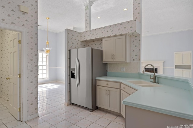 kitchen featuring decorative light fixtures, sink, ornamental molding, stainless steel refrigerator with ice dispenser, and a textured ceiling