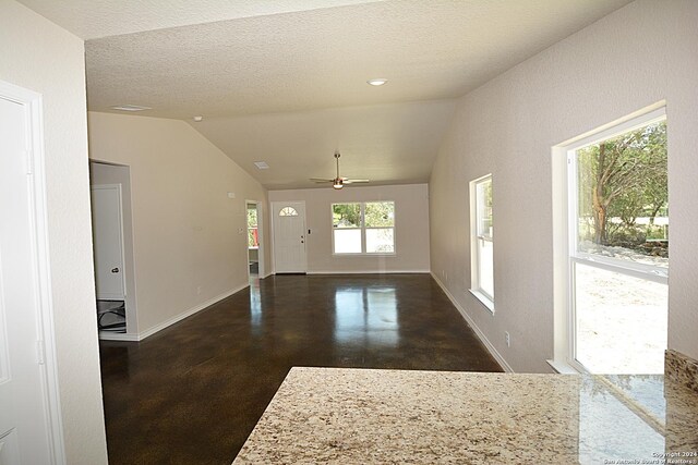 interior space with lofted ceiling, a textured ceiling, and baseboards