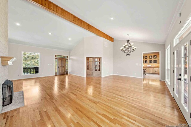 unfurnished living room with a chandelier, french doors, light hardwood / wood-style floors, and beam ceiling