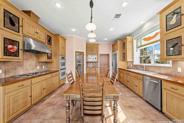 kitchen with tasteful backsplash, light tile patterned floors, hanging light fixtures, built in appliances, and sink