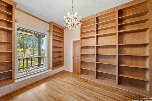 spacious closet with light hardwood / wood-style floors and an inviting chandelier