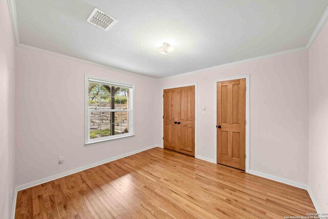 unfurnished bedroom with light wood-type flooring and ornamental molding