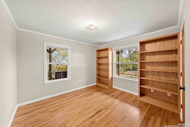 spare room with a healthy amount of sunlight, crown molding, and light wood-type flooring