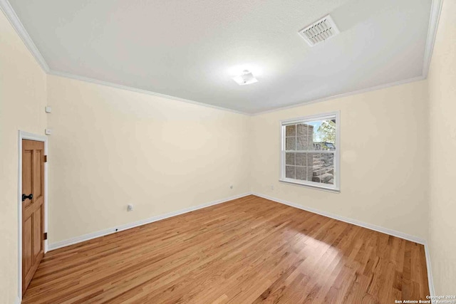 spare room featuring crown molding and light wood-type flooring