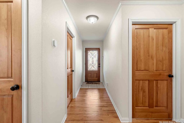 hallway featuring crown molding and light hardwood / wood-style flooring