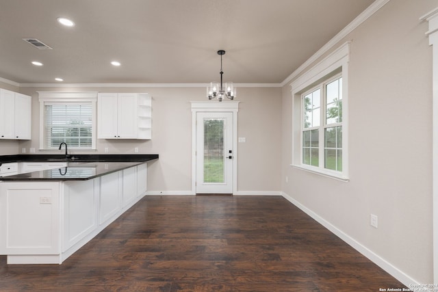 kitchen featuring plenty of natural light, kitchen peninsula, sink, decorative light fixtures, and white cabinetry