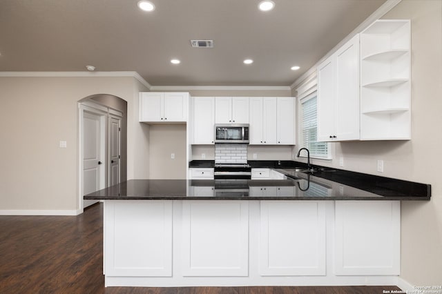 kitchen featuring kitchen peninsula, stainless steel appliances, white cabinetry, and dark stone counters