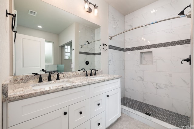 bathroom featuring tiled shower and vanity