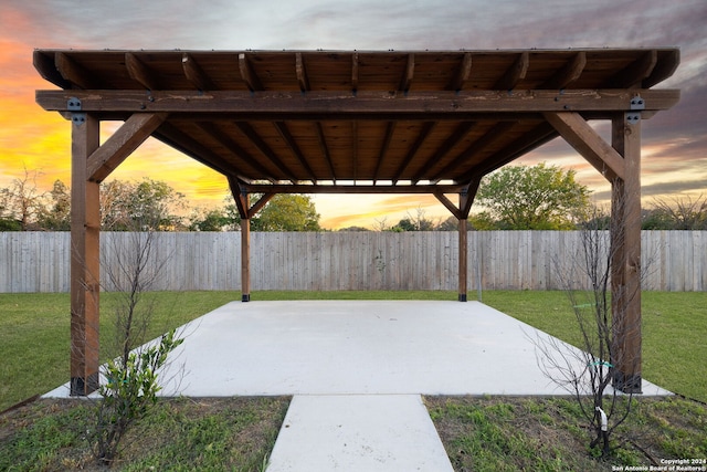 patio terrace at dusk featuring a yard