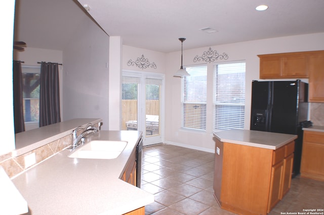 kitchen with a center island with sink, sink, hanging light fixtures, light tile patterned floors, and dishwasher