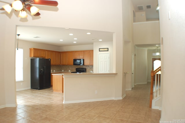 kitchen featuring black appliances, kitchen peninsula, decorative backsplash, light tile patterned flooring, and ceiling fan