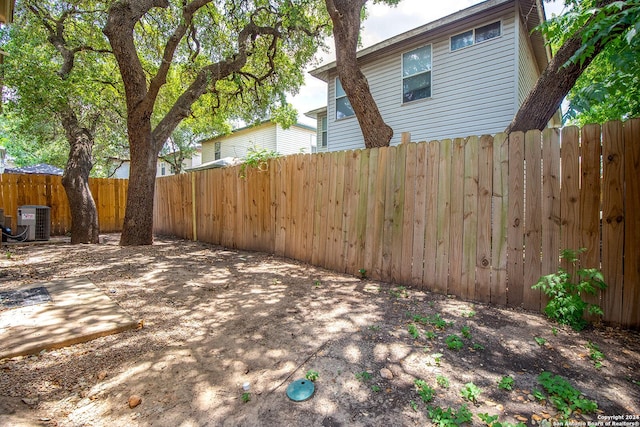 view of yard featuring central AC and fence