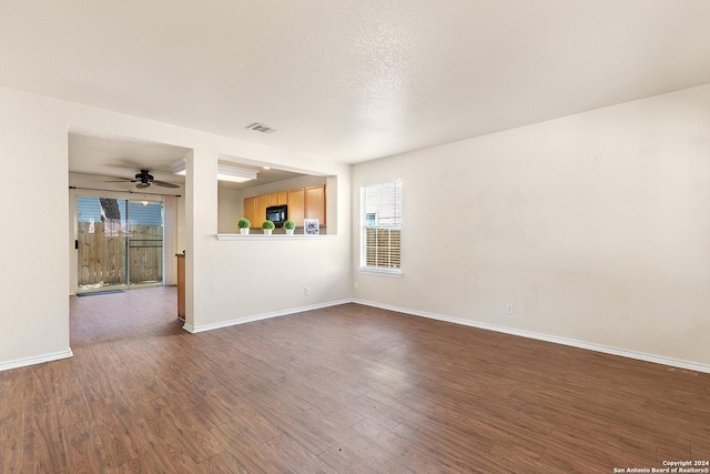 interior space featuring visible vents, a textured ceiling, dark wood finished floors, baseboards, and ceiling fan