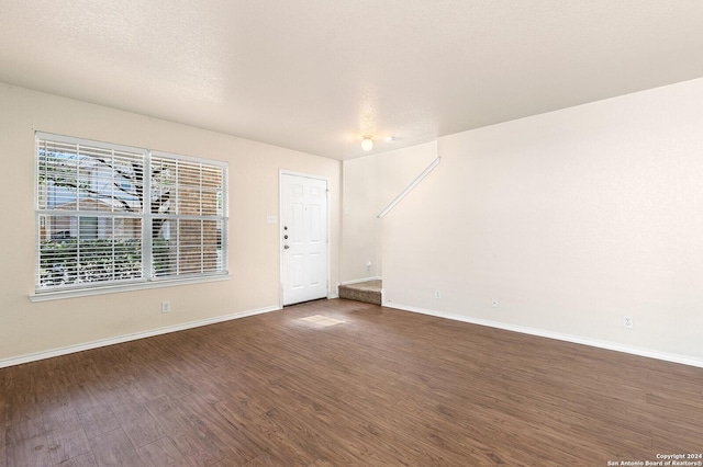 empty room featuring baseboards, a textured ceiling, and wood finished floors