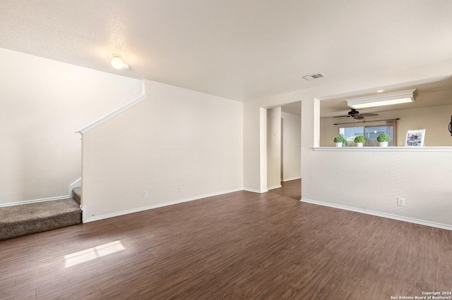 unfurnished living room with visible vents, baseboards, dark wood finished floors, stairs, and a ceiling fan