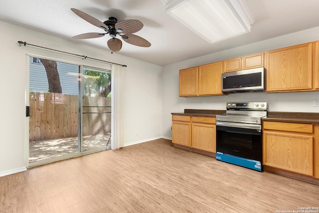 kitchen featuring a ceiling fan, dark countertops, stainless steel appliances, light wood-style floors, and baseboards