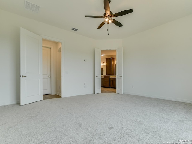 unfurnished bedroom featuring ceiling fan, light carpet, and connected bathroom