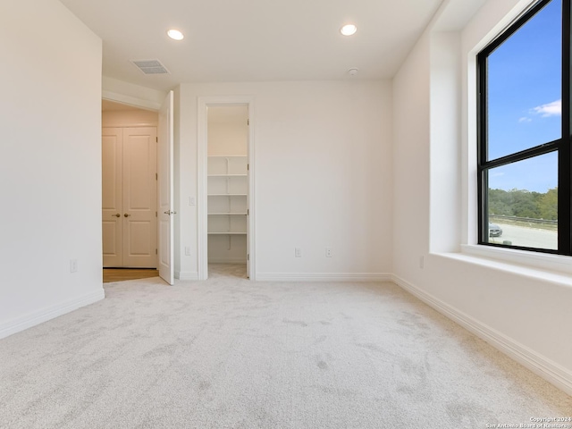 unfurnished bedroom with light carpet, a closet, and a walk in closet