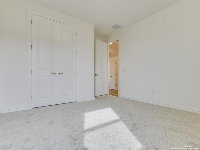 unfurnished bedroom featuring light carpet and a closet