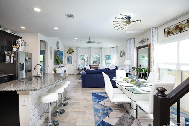 dining room with sink and ceiling fan with notable chandelier